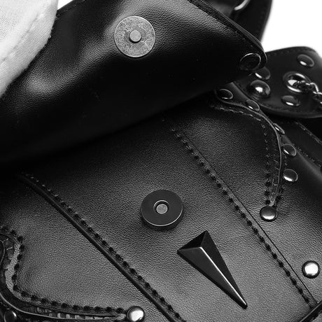 Close-up of a black leather waist bag featuring a pointed metal spike detail, silver studs, contrast stitching, and snap-button closures.