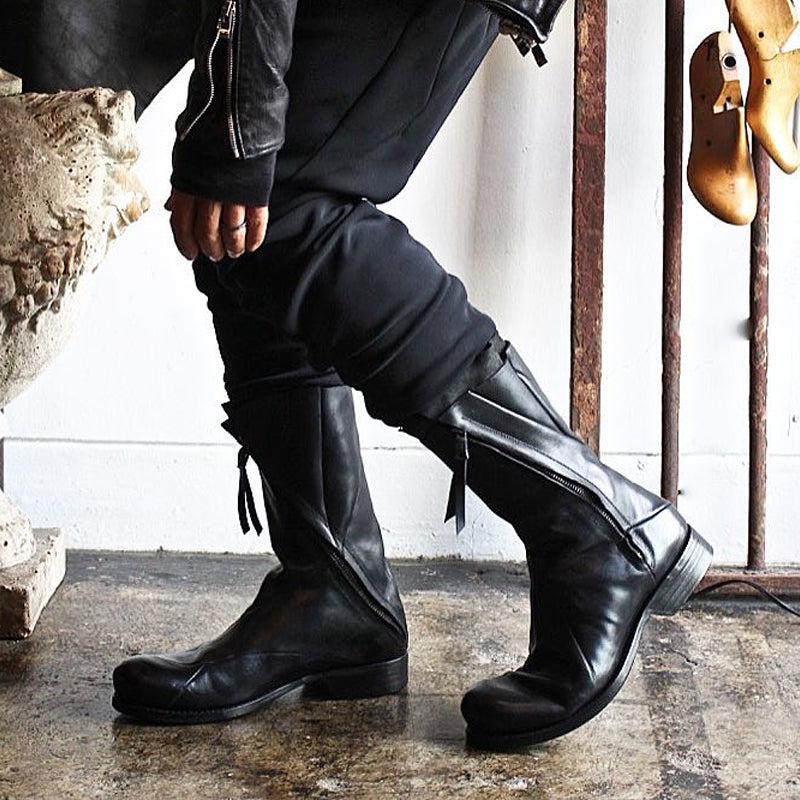 Men's black Japanese deconstructed leather boots with high shaft zipper and fringe detail, worn with dark outfit, Alternative Darkwear