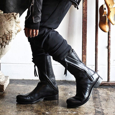 Men's black Japanese deconstructed leather boots with high shaft zipper and fringe detail, worn with dark outfit, Alternative Darkwear
