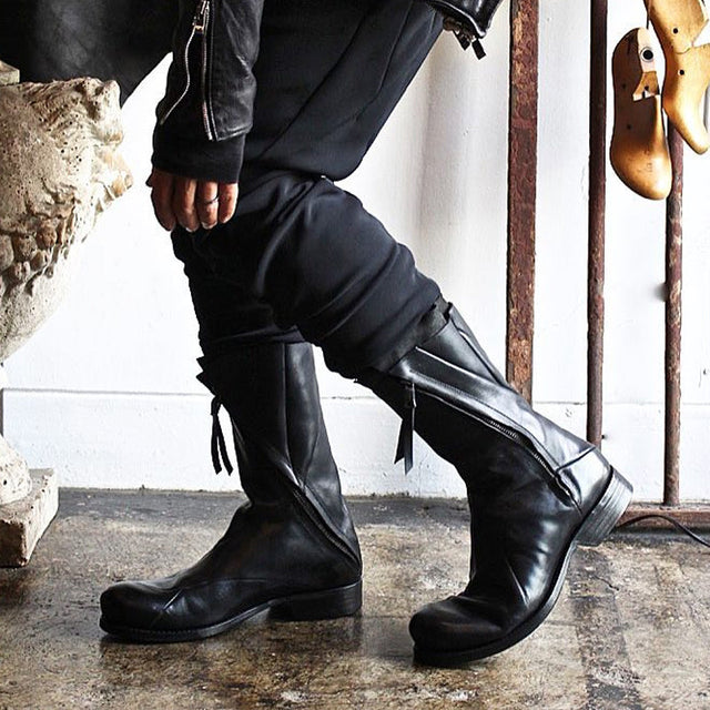 Men's black Japanese deconstructed leather boots with high shaft zipper and fringe detail, worn with dark outfit, Alternative Darkwear