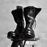 Pair of black high shaft deconstructed leather boots displayed on stool showing zipper and sculptural silhouette, Alternative Darkwear